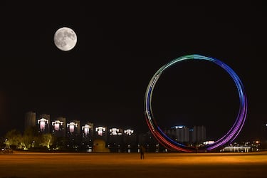 La luna llena del cazador se eleva en el cielo nocturno sobre una noria el 16 de octubre de 2024 en Weihai, provincia de Shandong, China.