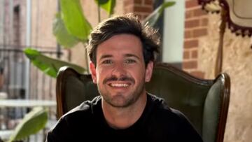 Foto de perfil del surfista Lance Appleby, sonriendo a cámara con un café en las manos y una planta detrás.