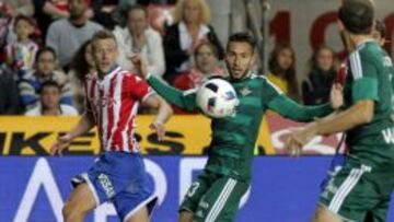 El centrocampista del Sporting de Gij&oacute;n &Aacute;lex Barrera centra el bal&oacute;n ante Francisco Varela, del Real Betis.