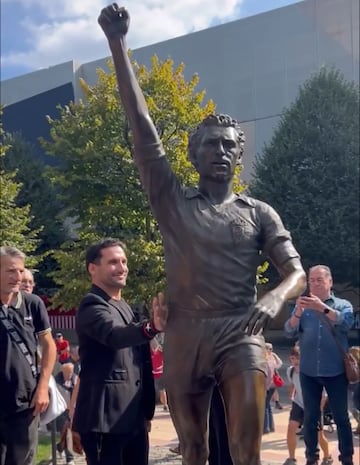 El artista Carlos García acaricia su obra, la estatua de Quini.