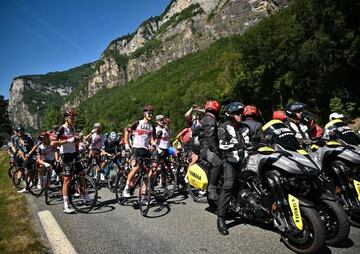 The pack of riders is temporarily immobilized by race regulators (R) due to protest action on the race route by environmental protestors during the 10th stage of the 109th edition of the Tour de France cycling race, 148,1 km between Morzine and Megeve, in the French Alps, on July 12, 2022. 