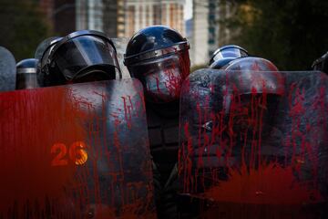 Los agentes de policía hacen guardia con sus escudos cubiertos de pintura roja durante una protesta realizada por maestros en contra de Los agentes de policía hacen guardia con sus escudos cubiertos de pintura roja durante una protesta realizada por maestros contra un nuevo plan de estudios establecido por el Ministerio de Educación de Bolivia, en La Paz.