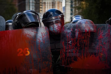 Los agentes de policía hacen guardia con sus escudos cubiertos de pintura roja durante una protesta realizada por maestros en contra de Los agentes de policía hacen guardia con sus escudos cubiertos de pintura roja durante una protesta realizada por maestros contra un nuevo plan de estudios establecido por el Ministerio de Educación de Bolivia, en La Paz.