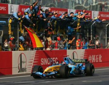 Renault's Formula One driver Fernando Alonso of Spain drives his Renault across the finish line to win as his team celebrates at the Shanghai Grand Prix October 16, 2005. REUTERS/Bobby Yip