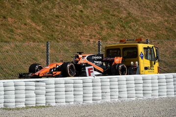 Un camión remolca el Mclaren de Fernando Alonso tras quedarse parado en medio del circuito de Montmeló.