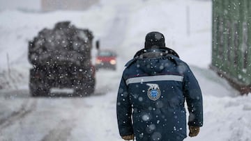 A man wearing an anorak with the logo of Arktikugol company on the back walks in the blizzard on May 7, 2022, in the miners&#039; town of Barentsburg, on the Svalbard Archipelago, northern Norway. - War may be far away but tensions from the Ukraine confli