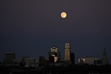 La luna se eleva tras un cartel antiguo en la cima de un edificio de apartamentos en el centro de la ciudad de Kansas City.