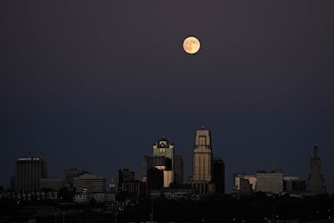 La luna se eleva tras un cartel antiguo en la cima de un edificio de apartamentos en el centro de la ciudad de Kansas City.