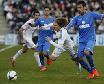 El centrocampista croata del Real Madrid Luka Modric cae ante el centrocampista del Getafe Juan Rodríguez durante el partido de la vigésimo cuarta jornada de liga de Primera División