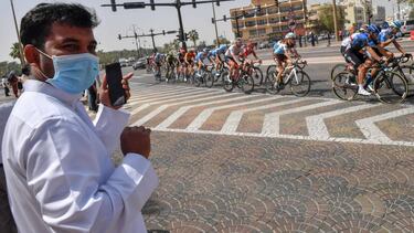 A man wearing a surgical masks looks on as the pack rides by during stage five the UAE Cycling Tour from al-Maroom to Jebel Hafeet, in Dubai on February 27, 2020. (Photo by Giuseppe CACACE / AFP)