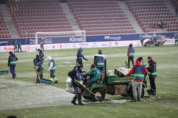 Operarios del club rojillo quitan la nieve del terreno de juego.
