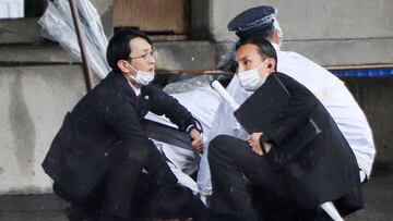 A man (bottom) is detained after throwing an apparent"smoke bomb" in Wakayama on April 15, 2023, where Japan's Prime Minister was due to give a speech. - Kishida was evacuated from the port in Wakayama after a blast was heard, but he was unharmed in the incident, local media reported on April 15. (Photo by JIJI Press / AFP) / Japan OUT (Photo by STR/JIJI Press/AFP via Getty Images)