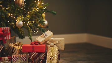 Photo of luxury gift boxes under Christmas tree, New Year home decorations, golden wrapping of Santa presents, festive tree decorated with garland, baubles, traditional celebration. Copy space NAVIDAD REGALOS REGALO