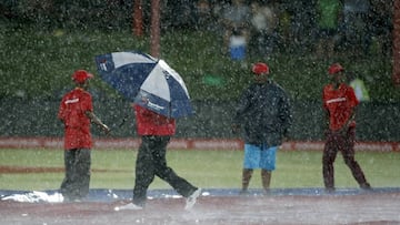 A worker holds an umbrella on the pitch after the first ODI cricket match between England and South Africa was stopped due to rain in Bloemfontein, South Africa.