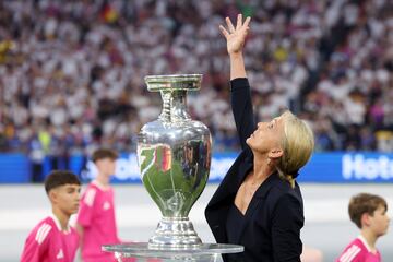 Heidi Beckenbauer, esposa de Franz Beckenbauer, levanta el brazo en recuerdo del legendario futbolista alemán junto a la copa Henri Delaunay, trofeo del torneo.