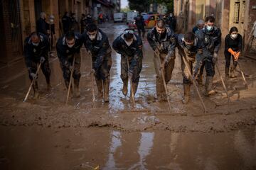 Miembros de la Policía Nacional española retiran el barro de las calles afectadas por las inundaciones en Masanasa, Valencia. 