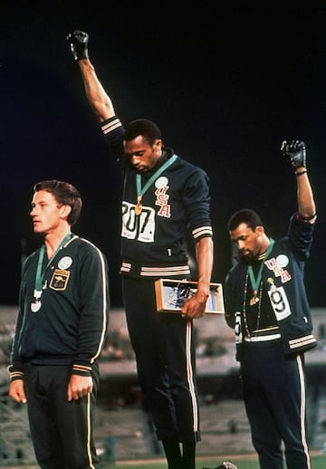 En los Juegos Olímpicos de verano de 1968 los corredores estadounidenses Tommie Smith (centro) y John Carlos (derecha) levantan sus puños con guantes negros en el pódium en protesta contra el racismo mientras sonaba el himno nacional estadounidense. Este 