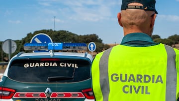 Badajoz, Spain. May 16, 2023. Civil guard agent equipped with his reflective vest, next to the patrol car on a road.