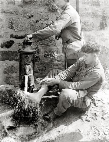 El soldado C. L. Scott de la 4.ª División de Infantería se está lavando los pies en una fuente pública. La ciudad fue liberada horas antes por el ejército estadounidense.