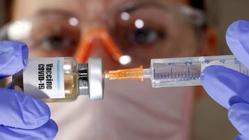 FILE PHOTO: A woman holds a small bottle labeled with a &quot;Vaccine COVID-19&quot; sticker and a medical syringe in this illustration taken April 10, 2020. REUTERS/Dado Ruvic/Illustration/File Photo