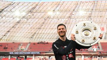 Bayer Leverkusen's Spanish head coach Xabi Alonso poses with the trophy after the German first division Bundesliga football match between Bayer 04 Leverkusen and FC Augsburg in Leverkusen, western Germany on May 18, 2024. Bayer Leverkusen have become the first team in Bundesliga history to go through a season unbeaten after a 2-1 home win over Augsburg on May 18, extending their season-long run to 51 games without defeat. (Photo by Sascha Schuermann / AFP) / DFL REGULATIONS PROHIBIT ANY USE OF PHOTOGRAPHS AS IMAGE SEQUENCES AND/OR QUASI-VIDEO