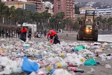Miembros del servicio de limpieza municipal de Málaga recogen restos de basura en la playa de La Malagueta.