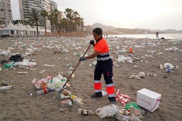 Un operario del servicio de limpieza municipal de M¨¢laga recoge restos de basura en la playa de La Malagueta.
