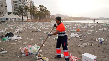 Un operario del servicio de limpieza municipal de Málaga recoge restos de basura en la playa de La Malagueta.