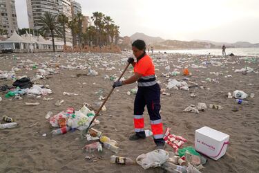 Un operario del servicio de limpieza municipal de Málaga recoge restos de basura en la playa de La Malagueta.