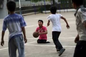 Qin Xulei se prepara para disparar una pelota de baloncesto vive en Yichuan condado, Luoyang, provincia de Henan. Qin, de 13 años, se encuentra entre los diez mejores alumnos de su escuela, perdió sus piernas en un accidente de coche cuando tenía tres años. Qin espera representar a China como parte de su equipo nacional de baloncesto de silla de ruedas en los Juegos Paralímpicos en el futuro.
