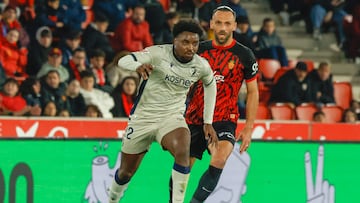 PALMA DE MALLORCA, 10/02/2025.- El defensa de Osasuna Enzo Boyomo (i) juega un balón ante Vedat Muriqi, de Osasuna, durante el partido de LaLiga de fútbol que RCD Mallorca y CA Osasuna disputan este lunes en el estadio de Son Moix, en Palma. EFE/Cati Cladera