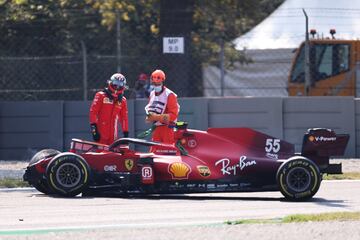 Carlos Sainz observa junto a un comisario de carrera el monoplaza siniestrado.