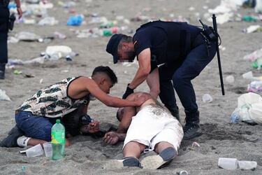 Un agente de la Policía Local atiende a una persona en la playa de La Malagueta. 
