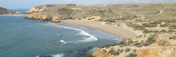 Playa situada en entorno natural. A 5 km dentro de las conocidas como Cuatro Calas, magnífica playa que junto a sus hermanas cuenta con una importante extensión de arenas doradas que se sumergen suavemente en un mar transparente. Abierta a levante está protegida del poniente y algo menos del lebeche. Tiene enfrente un pequeño islote rocoso de agudas aristas, conocido por los pescadores como ‘La Cama de los Novios’. 