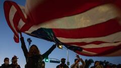 A woman waves a US flag as people celebrate in the Venice Beach neighborhood of Los Angeles, California after Joe Biden was declared winner of the 2020 presidential election on November 7, 2020. - Democrat Joe Biden urged unity on November 7 and promised 