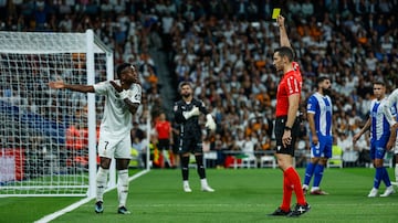 El colegiado Alejandro Muñiz Ruiz muestra tarjeta amarilla al delantero del Real Madrid Vinícius.