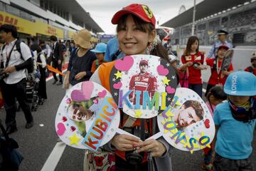 Una fan posa con "pay-pays" decorados con fotos de los pilotos Robert Kubica, Kimmi Raikkonen y Fernando Alonso.