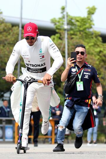 El piloto británico monta en un patinete eléctrico en el paddock.