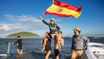 Elena Moreno, campeona del mundo de Wingfoil Wave en Brasil, saliendo del agua con la bandera española en mano.