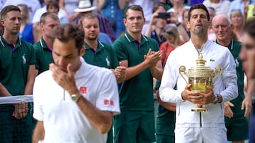 Novak Djokovic of Serbia holds the trophy as he watches watches Roger Federer of Switzerland after the Men's Singles Final on Centre Court during the Wimbledon Lawn Tennis Championships at the All England Lawn Tennis and Croquet Club at Wimbledon on July 14, 2019 in London, England.