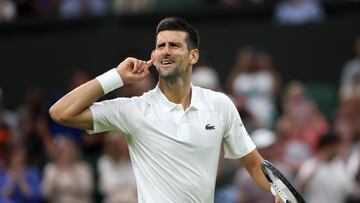 El tenista serbio Novak Djokovic se lleva el dedo al oído durante un partido en Wimbledon.