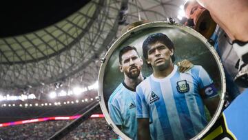 LUSAIL CITY, QATAR - DECEMBER 09: Argentina supporters show their support with a drum adorned with the images of Diego Maradona and Lionel Messi during the FIFA World Cup Qatar 2022 quarter final match between Netherlands and Argentina at Lusail Stadium on December 09, 2022 in Lusail City, Qatar. (Photo by Alex Livesey - Danehouse/Getty Images)