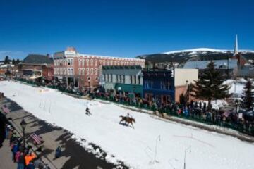 Un jinete lleva atado a su caballo a un esquiador que se aproecha de la fuerza del caballo para coger velocidad en la Avenida Harrison durante la 68º edición del Leadville Ski Joring en Leadville, Colorado.