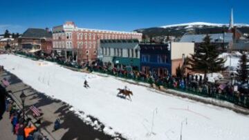 Un jinete lleva atado a su caballo a un esquiador que se aproecha de la fuerza del caballo para coger velocidad en la Avenida Harrison durante la 68º edición del Leadville Ski Joring en Leadville, Colorado. 