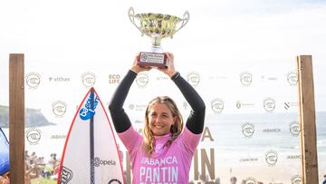 Leticia Canales con el trofeo de campeona de Europa de surf de la WSL en Pant&iacute;n, con un fotocall y la playa al fondo. 