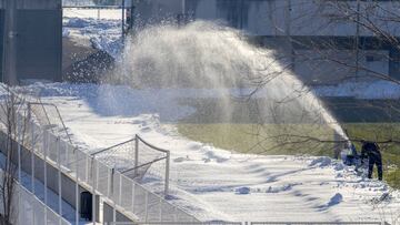 Operarios quitando nieve del césped de la Ciudad Deportiva.