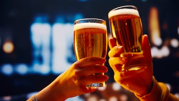 Hands holding lager light foamy big beer glasses and clinking. Two friends sitting in bar and drinking alcohol drinks. Concept of Beer Fest, party, celebration, taste, national traditions.