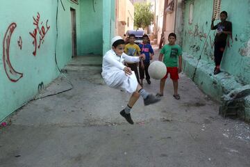 Un grupo de niños palestinos juegan al fútbol cerca del campo de refugiados de Al-Fawar en Hebrón, Cisjordania.
