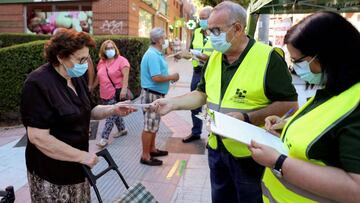 MADRID, 19/08/2020.- Voluntarios de la asociación de mayores Acumafu reparten mascarillas en un puesto situado a la entrada del Mercadillo de la localidad madrileña de Fuenlabrada, este miércoles. EFE/Rodrigo Jiménez