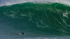 Una ola grande rompe en La Vaca (Cueto, Santander, Cantabria) mientras tres surfistas subidos a sus tablas de surf se lo miran y uno de ellos se&ntilde;ala la ola con su dedo. 